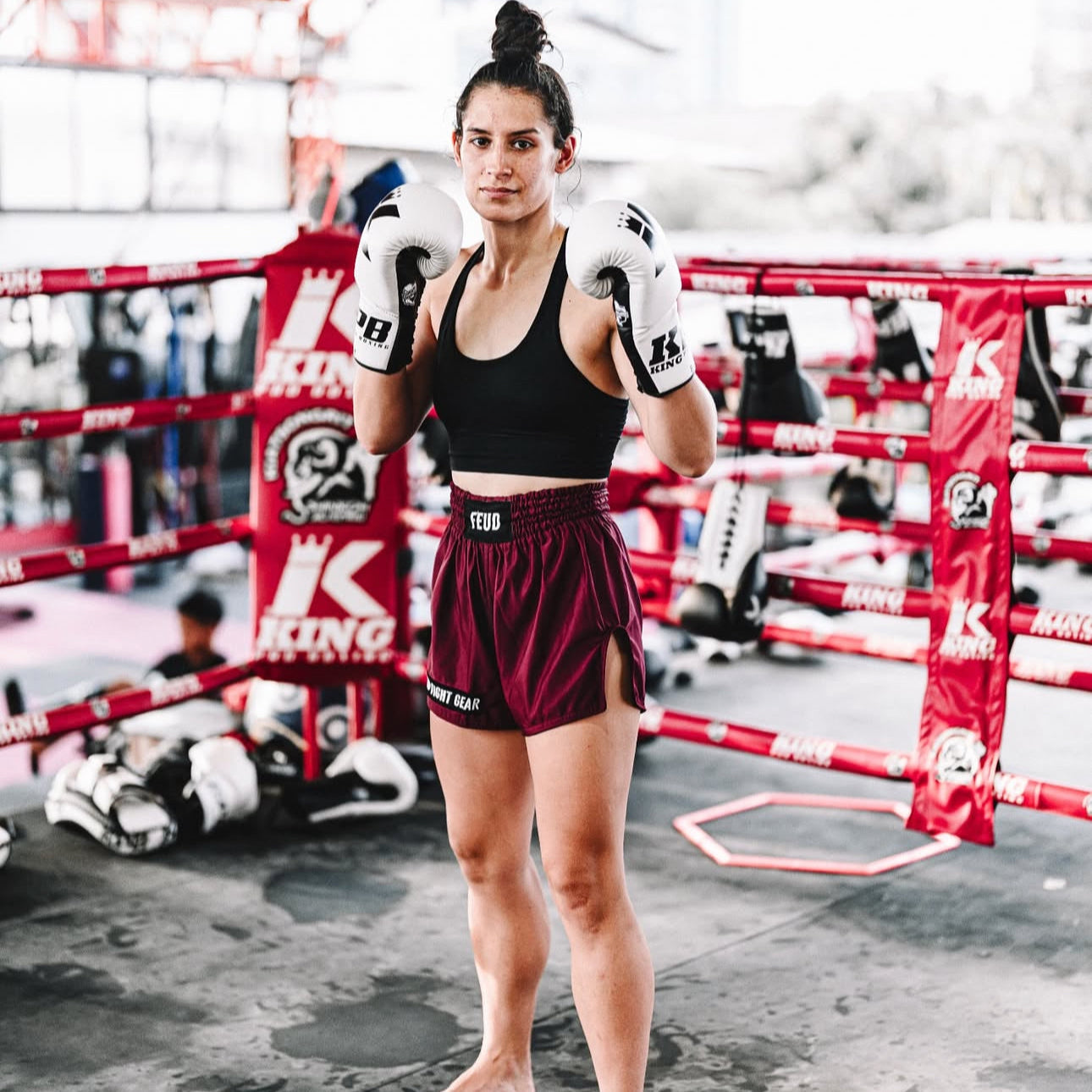 Woman in Burgundy Thai Shorts by Feud Fight Gear in boxing ring