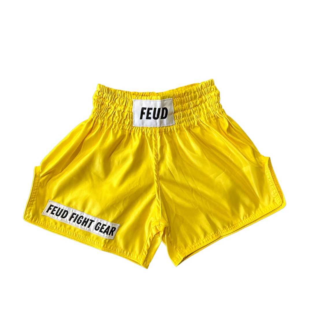 Bright yellow Muay Thai shorts with elastic waistband and Feud logo